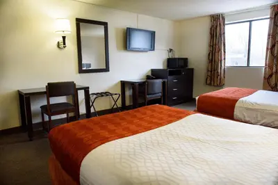 a hotel room with two beds and a desk and a mirror at Americas Best Value Inn New Paltz in New Paltz