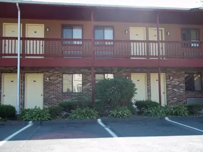 a large brick building with white doors and a balcony at Naugatuck Motor Lodge in Naugatuck