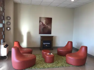 a waiting room with red chairs and a fireplace at Grantmoor Motor Lodge in Newington