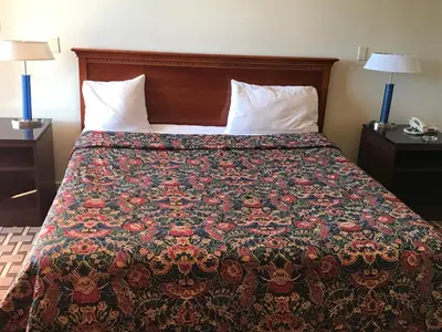 a bed in a hotel room with a colorful bedspread at Grantmoor Motor Lodge in Newington