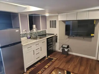 a kitchen with white cabinets and a stainless steel refrigerator at The Subterranean Haven in Mount Vernon