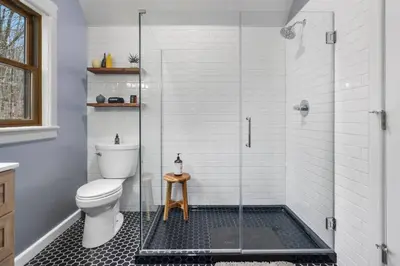 a bathroom with a toilet and a glass shower at Lakefront Log Cabin, Private Lake Access w/Peloton in Livingston Manor