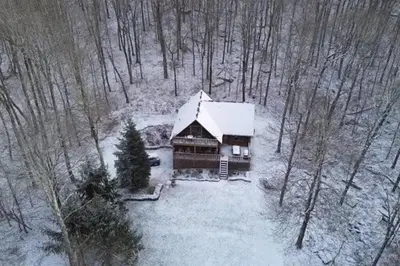 a log cabin with snow on it in the woods at Lakefront Log Cabin, Private Lake Access w/Peloton in Livingston Manor
