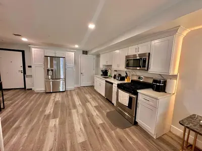 a kitchen with white cabinets and stainless steel appliances at The Modern Suite - 2BR Close to NYC in Paterson