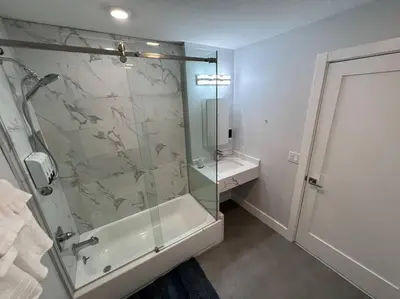 a bathroom with a shower with a glass door at The Cozy Suite - 1BR with Free Parking in Paterson