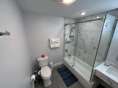 a bathroom with a toilet and a glass shower at The Cozy Suite - 1BR with Free Parking in Paterson