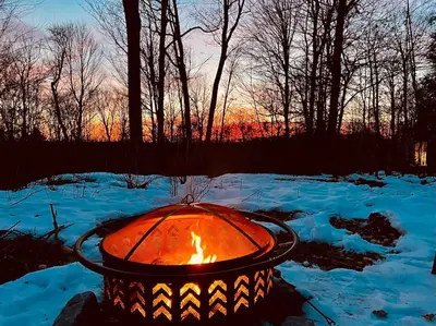 a fire pit in the snow with the sunset in the background at renovatedhot tubnear skiingtubingcozy & chic in Monticello