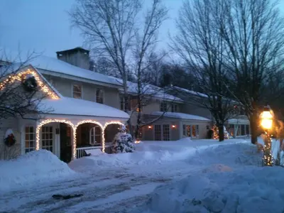 a house covered in snow with christmas lights on it at Deerhill Inn in West Dover