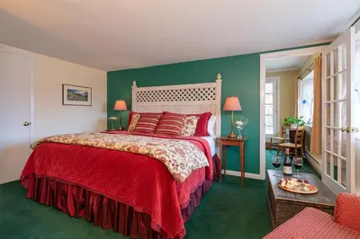 a bedroom with a large bed with a red blanket at Deerhill Inn in West Dover