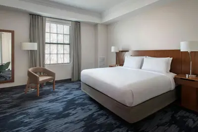 a hotel room with a large bed and a chair at Fairfield Inn & Suites by Marriott Albany Downtown in Albany