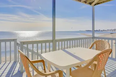a white table and chairs on a balcony with the beach at Cheerful 3 Bedroom Beach Front Cottage with Fire Place in Milford