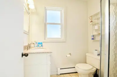 a white bathroom with a toilet and a sink at Cheerful 3 Bedroom Beach Front Cottage with Fire Place in Milford