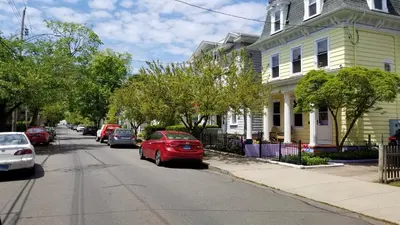 a red car parked on a street in front of houses at Spacious Getaway by Wooster Square! in New Haven