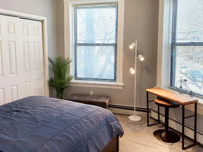 a bedroom with a bed and a desk and windows at Spacious Getaway by Wooster Square! in New Haven