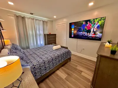 a bedroom with a bed and a flat screen tv at The Classy Suite - 2BR with Free Parking in Paterson