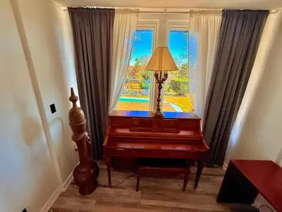 a lamp sitting on top of a piano in front of a window at Ultimate Luxury Villa - Pool, Sauna, Hot Tub & More in Paterson