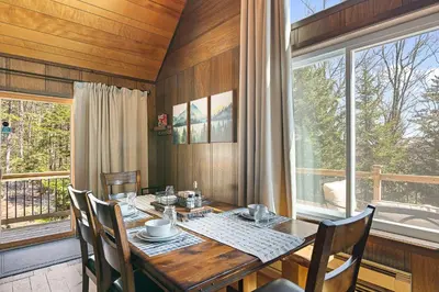 a dining room with a table and chairs and windows at Crooked Ear Cabin in Wilmington