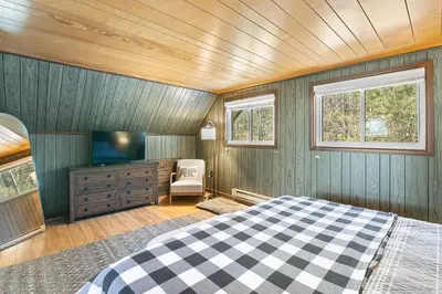a bedroom with a bed and a flat screen tv at Crooked Ear Cabin in Wilmington