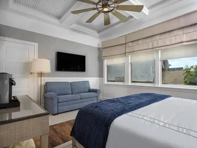 a bedroom with a bed and a couch and a ceiling fan at The Northport Hotel in Northport
