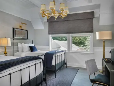 a bedroom with two beds and a window and a chandelier at The Northport Hotel in Northport