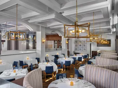 a restaurant with white tables and blue chairs at The Northport Hotel in Northport