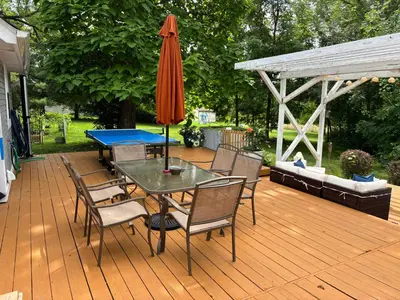 a deck with a table with a ping pongopter and an umbrella at Country House in Catskills in Saugerties