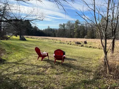 two red chairs sitting in the grass in a field at Country House in Catskills in Saugerties