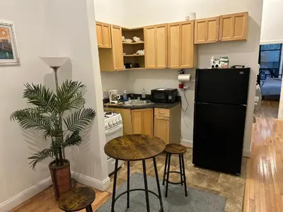 a small kitchen with a black refrigerator and stools at Townhouse in Uptown Manhattan in New York