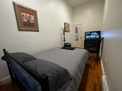a bedroom with two beds and a flat screen tv at Townhouse in Uptown Manhattan in New York