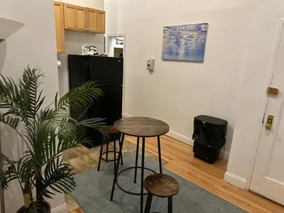 a kitchen with a table and two stools and a refrigerator at Townhouse in Uptown Manhattan in New York