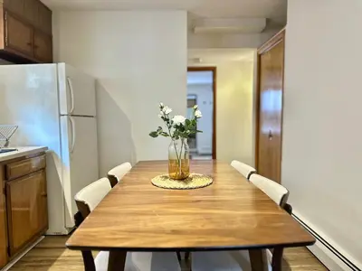 a kitchen with a wooden table with a vase of flowers on it at Downtown New Haven by Yale & Little Italy - AO Destinations in New Haven