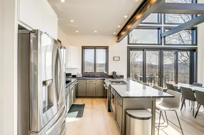a kitchen with a stainless steel refrigerator and counters at Custom Windham Mtn Villa with Pool, Theater and Views! in Windham