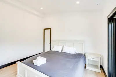 a white bedroom with a bed and a mirror at Custom Windham Mtn Villa with Pool, Theater and Views! in Windham