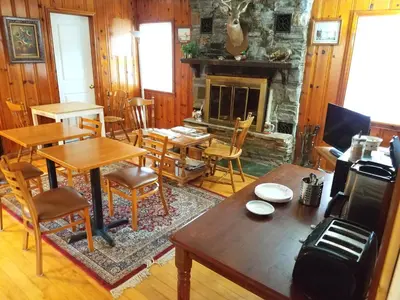 a living room with tables and chairs and a fireplace at Black Bear Lodge in Prattsville