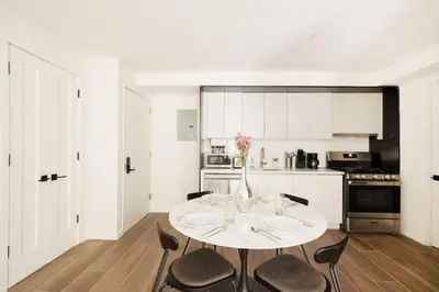 a white kitchen with a table and chairs at Massive 1BR w Private Patio in Upper East Side in New York