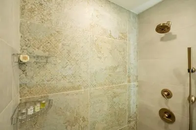 a bathroom with a shower with a tiled wall at Massive 1BR w Private Patio in Upper East Side in New York