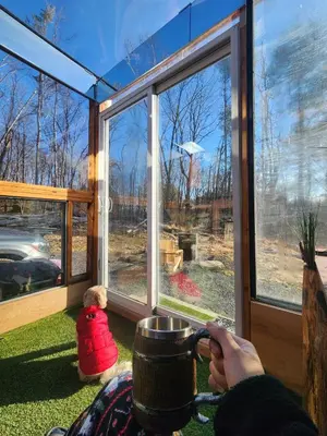 a person holding a coffee cup in front of a window at The Dome house near Hunter and Hudson in Catskill
