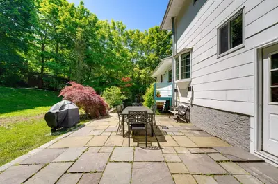 a patio with tables and chairs next to a house at NYC-Area Escape Near River, Trails and MTA! in Ossining
