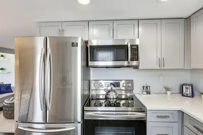 a kitchen with a stainless steel refrigerator and microwave at Modern Terryville Cottage with Deck and Lake View! in Terryville