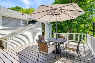 a patio with a table and chairs and an umbrella at Modern Terryville Cottage with Deck and Lake View! in Terryville