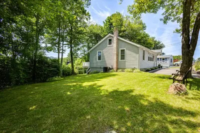 a home with a yard with a house at Modern Terryville Cottage with Deck and Lake View! in Terryville