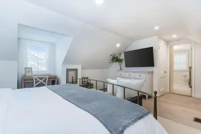 a white bedroom with a bed and a flat screen tv at Stay at Black Rock Harbor in Bridgeport