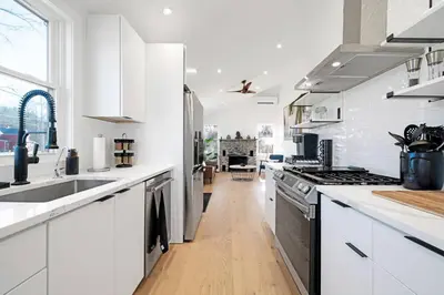 a kitchen with white cabinets and a wooden floor at New Paltz Zen Wellness Cabin w/ Hot Tub in New Paltz
