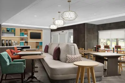 a living room with a couch and tables and chairs at Home2 Suites By Hilton Poughkeepsie in Poughkeepsie
