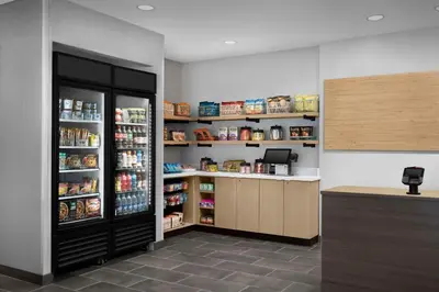 a kitchen with a refrigerator and shelves with food at Home2 Suites By Hilton Poughkeepsie in Poughkeepsie