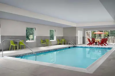 a pool in a hotel room with chairs and tables at Home2 Suites By Hilton Poughkeepsie in Poughkeepsie