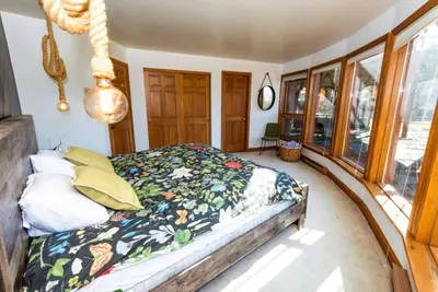 a bedroom with a bed in a room with windows at Luxury Mountain Mansion Huge Pool, Sauna, 7000sqft in Windham