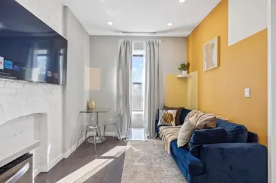a living room with a blue couch and a fireplace at SWJ544 - Spacious 5BR with Chef's Kitchen in New York