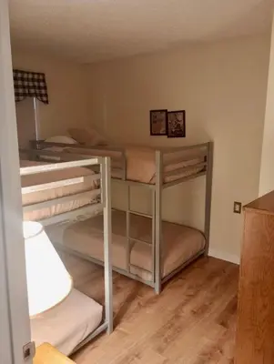 two bunk beds in a room with wood floors at Cozy Ski in out Cabin in Berkshire Resort in Hancock