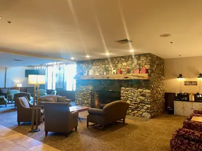 a lobby with chairs and a stone fireplace at Cozy Ski in out Cabin in Berkshire Resort in Hancock